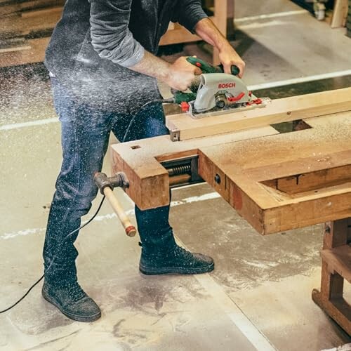 Hombre cortando madera con una sierra eléctrica en un taller
