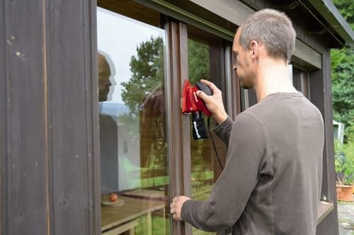 Hombre limpiando una ventana con herramienta eléctrica.